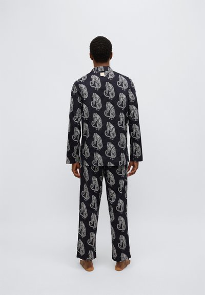 Set di pigiama nero con pattern ripetuti di tigri bianche. Camicia a maniche lunghe con colletto e pantaloni ampi. Tessuto dalla texture liscia.