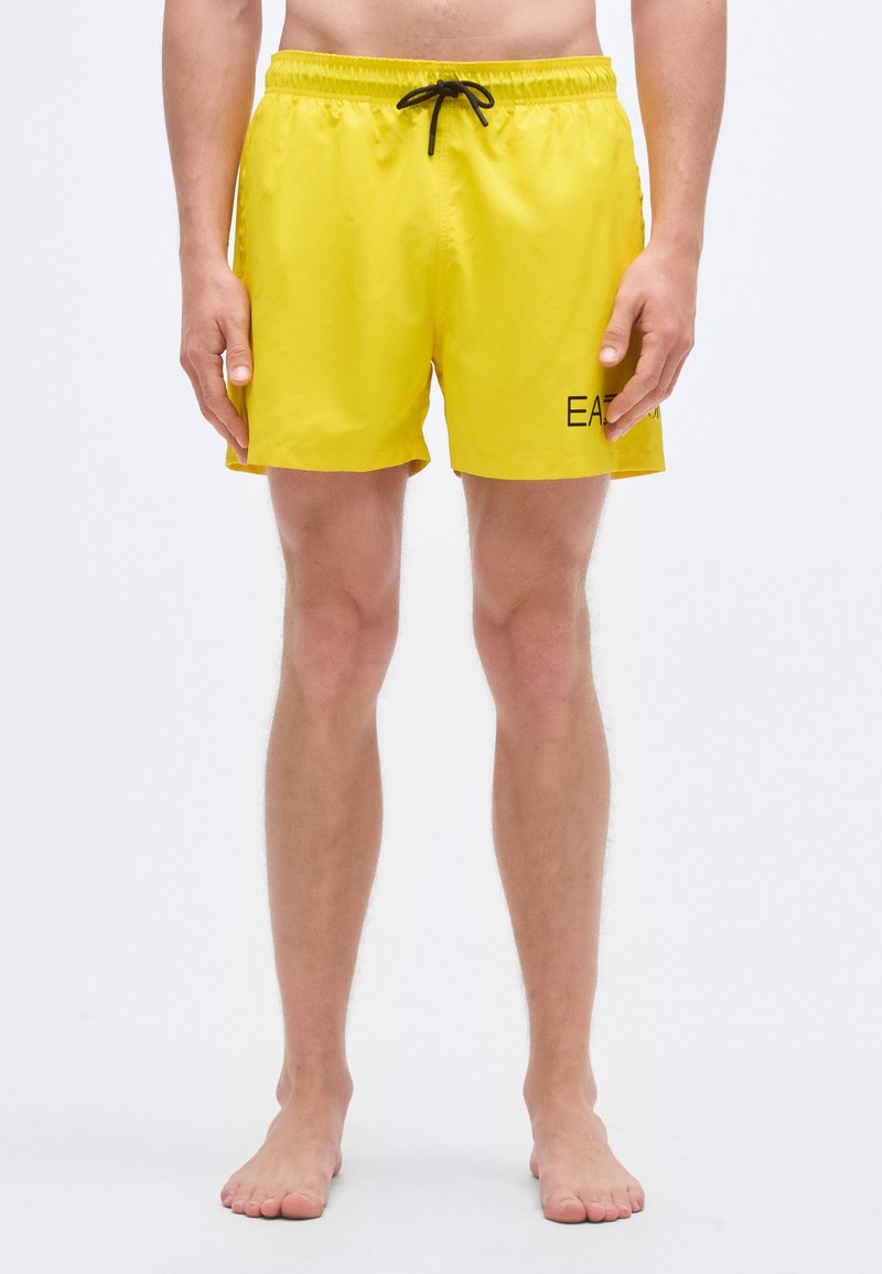 Dzelteni peldbikses ar elastīgu jostu un melnu auklu. Kreisajā pusē ir melns logotips. Viegls poliestera materiāls.