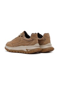 Zapatillas de ante marrón claro con una suela de goma crema gruesa, punta redonda y costuras en contraste. Cuenta con cierre de cordones y cuello acolchado.