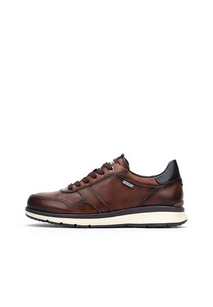 Zapatilla de cuero marrón con textura perforada, acentos negros y suela media blanca. Cuenta con cordones y un logo. Diseño atlético clásico.