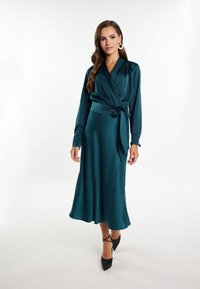 Teal Wickelkleid aus Satin mit langen Ärmeln, tailliertem Schnitt und Midilänge. Hat eine glatte Textur und eine elegante Drapierung.