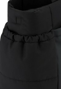 Mustat, pörröiset takit, joissa on kerrostettu kaula-aukko. Ominaisuudet sileä kangas, näkyvät saumat ja pehmeä tekstuuri. Ei näkyviä metalliosia.