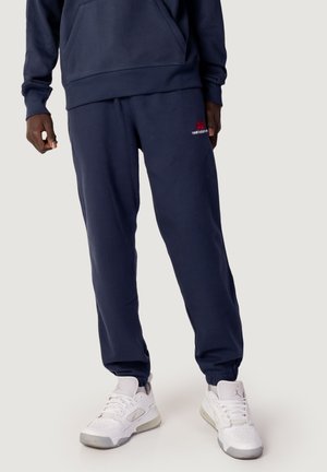 Pantalones de chándal azul marino hechos de una mezcla de algodón, con un corte holgado, puños acanalados y un pequeño logo rojo en el muslo izquierdo.