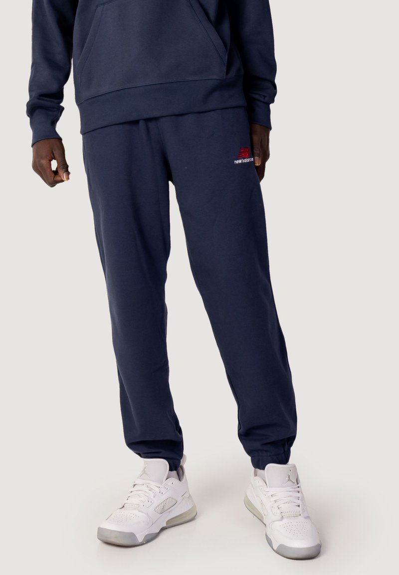Pantalones de chándal azul marino hechos de una mezcla de algodón, con un corte holgado, puños acanalados y un pequeño logo rojo en el muslo izquierdo.