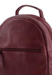 Maroon leather backpack featuring a rounded shape, front zipper pocket, and embossed "VENEZIA" logo on the upper section. Smooth texture.