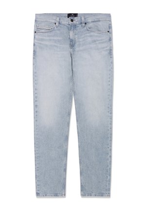 Lichtblauwe verweerde spijkerbroek met vijf zakken en riemlussen, plat neergelegd met zichtbare voorkant met knopen en ritssluiting.