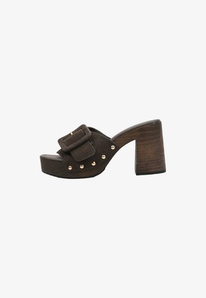 Mule marrón de ante con punta abierta, tacón bloque de madera grueso, hebilla grande de ante y detalles de tachuelas metálicas a lo largo del lateral.