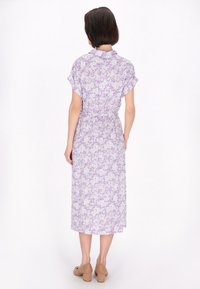 Abito midi floreale in viola chiaro con maniche corte, vita cintata e tessuto fantasia con fiori bianchi. Scarpe con tacco a blocco in legno.