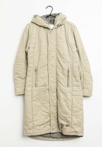 Beige lång vadderad vinterjacka med huva, frontdragkedja och tryckknappar, två fickor med dragkedja, hängande på en svart klädhängare.