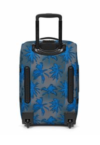Valigia trolley con manico telescopico nero e motivo con palme blu, in piedi su due ruote nere su sfondo bianco.
