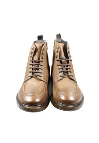 Stivaletti alla caviglia in pelle marrone con punta arrotondata, design con lacci, dettagli decorativi in metallo e cerniere laterali. Finitura testurizzata e dettagli cuciti.