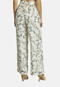 Bloemrijke wijde broek van lichtgewicht stof, met een crèmekleurige achtergrond en groene bladeren en roze bloemen. Elastische tailleband en relaxed fit.