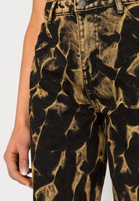 Schwarz-gelbe Batik-Jeans aus Denim mit strukturierter Oberfläche, hohe Taille, Fronttaschen und Knopfverschluss.