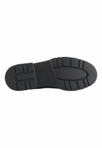 Zwarte rubberen schoenzool met een gestructureerd oppervlak, voorzien van meerdere groeven en ribbels voor grip. Toont de merknaam "Nine West."