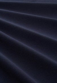 Tessuto blu scuro con una texture liscia, caratterizzato da leggere pieghe diagonali e un leggero lucido, che suggerisce un materiale morbido e traspirante.