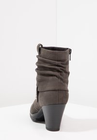 Bottine en cuir gris avec un design ample, fermeture éclair latérale et talon effilé. Tige texturée, finition lisse et légère brillance.