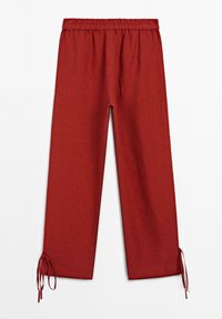 Pantaloni rossi in lino con un design a gamba larga, vita elastica e polsini legati alle caviglie. Tessuto leggero e colore uniforme.