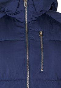 Marineblauwe gewatteerde jas met een capuchon, voorzien van een gouden ritssluiting en een horizontaal gestikt ontwerp. Glad textuur met glanzende hardware accenten.