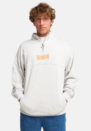 Hellgrauer Reißverschluss-Sweatshirt mit hohem Kragen, featuring einem orangefarbenen Textgrafik auf der Brust, lockere Passform und gerippte Bündchen.