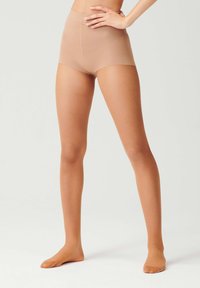 Shorts beige a vita alta con una texture liscia. Il tessuto è elasticizzato e aderente, raggiungendo la parte centrale della coscia. Nessun hardware o motivo visibile.