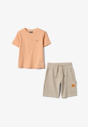 Camiseta de manga corta a rayas naranjas y blancas con bolsillo en el pecho y pantalones cortos beige con textura, cordón y parche en el bolsillo lateral.