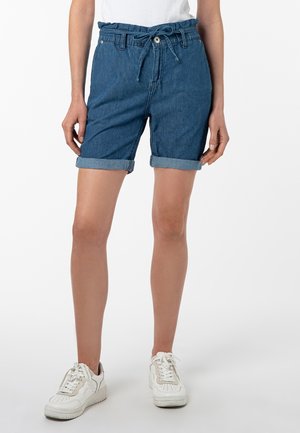 Denimshorts mit lockerer Passform, blauer Farbe, umgeschlagenen Säumen, elastischem Bündchen mit Kordelzug und Fronttaschen. Kombiniert mit weißen Sneakers.