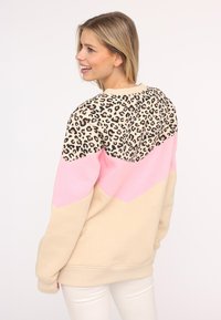 Sweatshirt à imprimé léopard avec un design en blocs de couleurs rose et beige. Tissu doux, coupe décontractée et poignets côtelés.