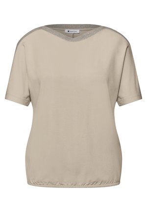 Blouse beige à manches courtes avec finition scintillante subtile sur l'encolure ronde et ourlet élastiqué, vue de face.