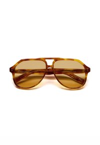 Occhiali da sole tortoise marroni con montatura geometrica, lenti colorate e dettagli del ponte ritagliati. Presenta sottili accenti in metallo sulle stecche.