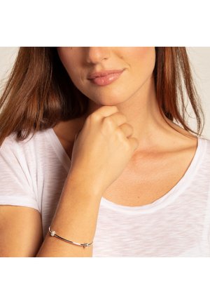 Silberarmband mit einer glatten, polierten Oberfläche. Verfügt über einen sicheren Verschluss und dekorative Knotenakzente. Trägt man am Handgelenk mit einem leichten Hemd.