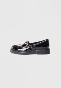 Black patent leather loafers with a low platform sole, featuring a small gold buckle accent and stitching details along the upper.