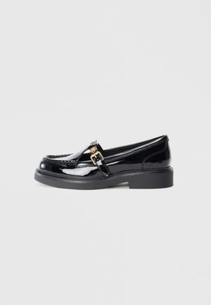 Black patent leather loafers with a low platform sole, featuring a small gold buckle accent and stitching details along the upper.