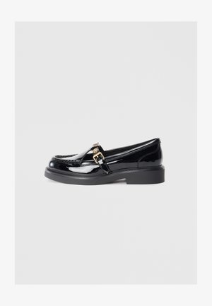 Mustat lakknahast loafers madala platvormi tallaga, millel on väike kuldne lukuaktsent ja õmblusteenused ülemise osa ääres.