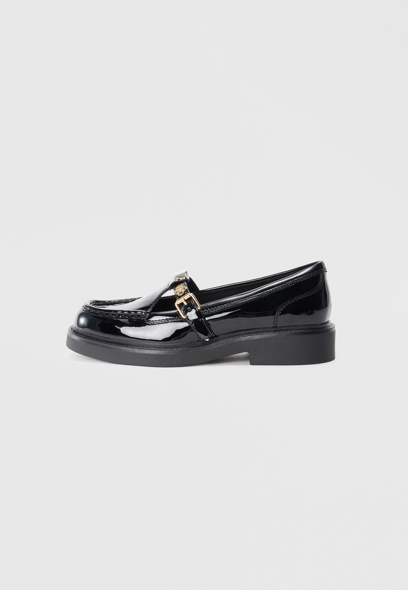 Black patent leather loafers with a low platform sole, featuring a small gold buckle accent and stitching details along the upper.