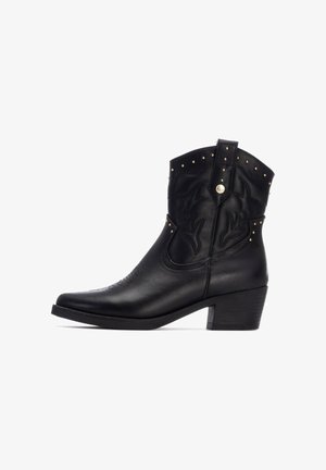 Bota vaquera de cuero negro con bordado estilizado, tachuelas doradas en la parte superior, punta afilada y tacón apilado.