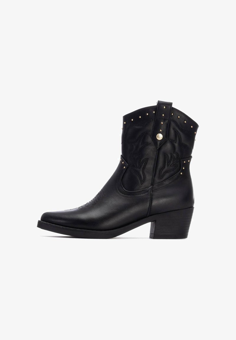 Bota vaquera de cuero negro con bordado estilizado, tachuelas doradas en la parte superior, punta afilada y tacón apilado.