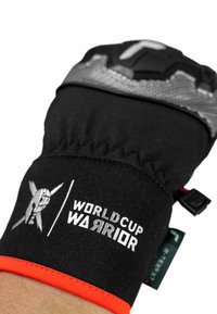 Schwarze Fäustlinge mit gepolstertem Design, orangefarbenen Akzenten und grauem, strukturiertem Oberteil. "WORLD CUP WARRIOR" Logo in Weiß aufgedruckt.