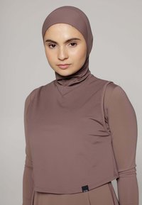 Bruine getailleerde top met een hoge hals, gemaakt van glad, rekbaar materiaal. Het ontwerp heeft lange mouwen en een bijpassende hijab van hetzelfde materiaal.