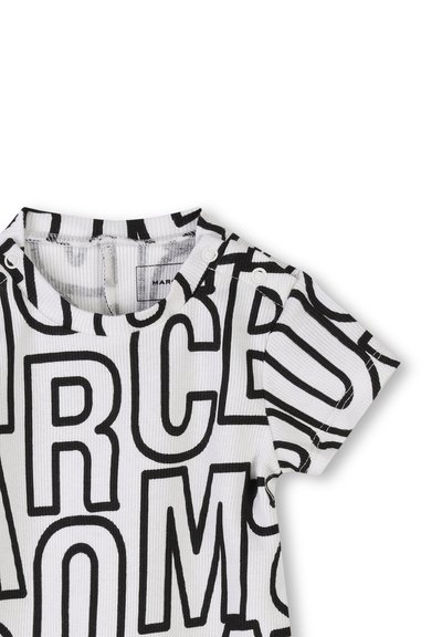Chemise à manches courtes rayée noir et blanc avec un grand motif texte. Le tissu est côtelé avec des boutons-pression à l'épaule pour un enfilage facile.