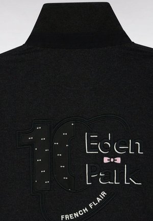 L'arrière de la veste noire montre "10 Eden Park" brodé avec de petits nœuds papillon blancs à l'intérieur du chiffre 10 et "French Flair" en dessous.