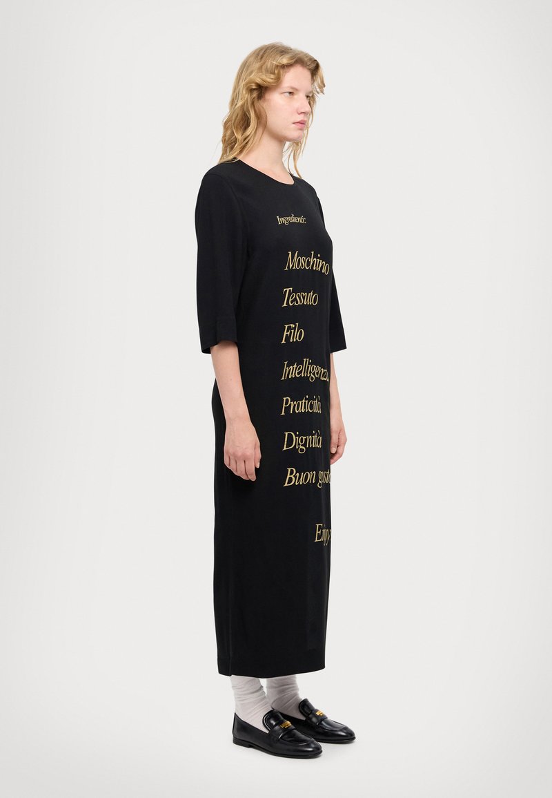 Black knee-length dress featuring gold text elements. Short sleeves, crew neck, and a relaxed fit. Accented with a minimalist design.