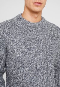 Strickpullover in einem melierten Marineblau- und Grauton, mit gerippter Textur und rundem Ausschnitt.