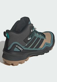 Czarno-turkusowe buty do wędrówek z teksturowaną, brązową siateczką, wyściełanym kołnierzem kostki oraz solidną, brązową podeszwą dla lepszej przyczepności. Zawiera GORE-TEX.
