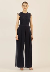 Mono azul marino con corsé de encaje, dise�ño sin mangas, pantalones amplios plisados y una cinturilla lisa, combinado con tacones plateados con tiras.
