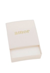 Scatola rettangolare di colore chiaro con una superficie liscia, con la parola "amor" in testo dorato sul coperchio. Interno vuoto.
