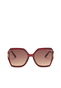 Lunettes de soleil rouges géométriques oversize avec verres dégradés marron et accents décoratifs dorés sur les bords de la monture.