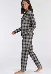 Black and white plaid pajama set with a button-up top featuring a chest pocket and matching pants. Made of soft fabric with a relaxed fit.
