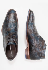 Chaussures en cuir à motif crocodile dans des tons de bleu et de marron, avec un bout pointu, un laçage à l'avant et un talon en bois avec un accent bleu.