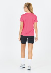 Lyserød kortærmet sportsbluse parret med sorte cykelshorts. Sættet har et elegant, tætsiddende design, perfekt til sportsaktiviteter.