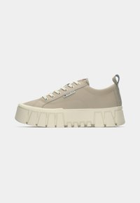 Sneaker beige con suola piatta chunky beige, dotate di occhielli in metallo e lacci, e un inserto sul tallone con un dettaglio di colore contrastante.